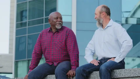 Positive smiling calm elderly men African American and European sitting outdoors Stock Footage 162071463