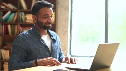 Positive smiling Indian freelancer guy using laptop for virtual meeting at Video stock 158926471