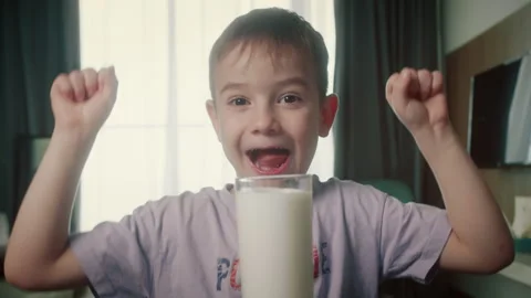 Positive smiling kid having breakfast at home. Cute boy drinking milk and eating Stock Footage 317724553