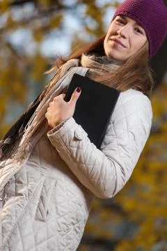 Positive student with book in hands in the fall park Stock Photos