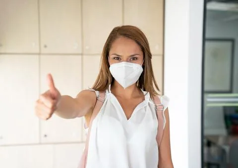 Positive student using a facemask with thumb up at university. Stock Photos