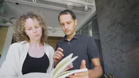 Positive woman draws in notebook talks to business partner Stock Footage 253280484