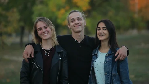 Positive young boy with two pretty girls in the autumn park Видео 96512916
