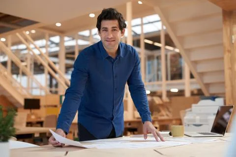 Positive young businessman sorting documents at an office desk Stock Photos
