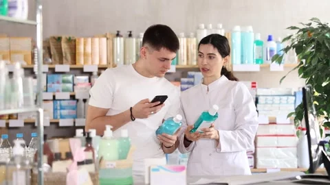 Positive young guy buyer at pharmacy choosing best mouthwash, scan QR code Stock Footage 320448096