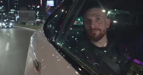 Positive young guy in traveling on the back seat of an uber car looking out the Stock Footage 191018482