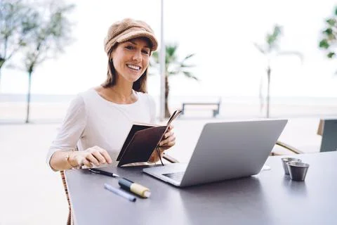 Positive young lady taking notes in street cafe Stock Photos