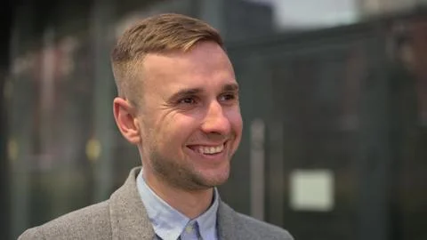 Positive young man in jacket posing in the city. Slow motion Stock Photos