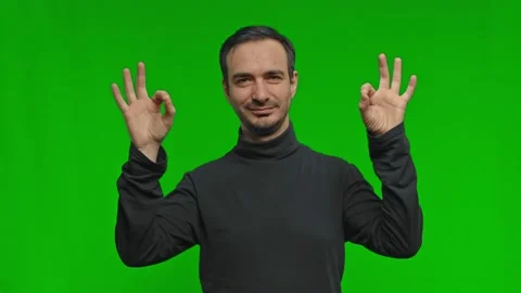 Positive young man smiles to camera. Guy showing OK sign over green background Stock Footage 170132847