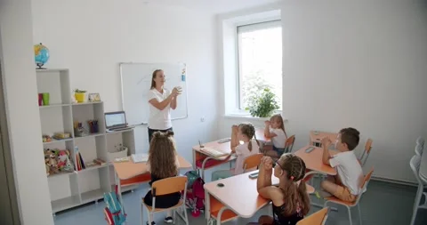 Positive young teacher does developing exercises for fingers in light living Stock Footage 148959704
