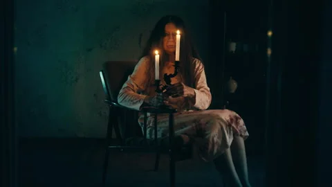 Possessed old witch holding burning candles while sitting in chair, black magic Stock Footage 260068906