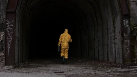 Post- apocalyptic concept. A man in a hazmat suit walks into a dark tunnel Stock Footage 126851817