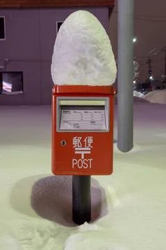 Post box with snow on top of it during heavy snowfall in Winter at night Stock Photos