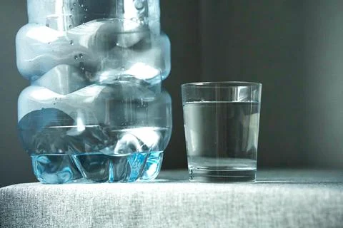 Post an empty plastic bottle and a glass filled with water Stock Photos