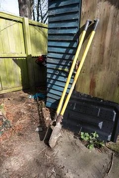 Post hole digger hand tool equipment leaning on old wooden shed Stock Photos
