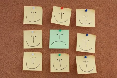 Post it notes with smiley face and sad faces on bulletin board Stock Photos