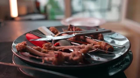 Post-Meal Scene Leftover Chicken Bones and Scattered Cutlery Stock Footage 305370253