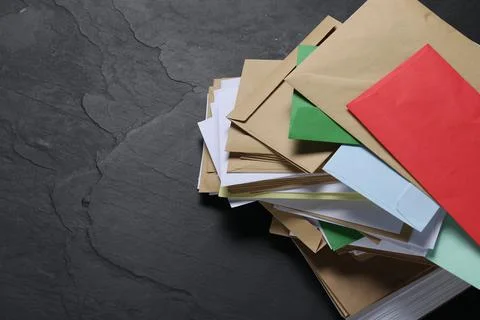 Post office. Stack of different paper envelopes on black table, above view... Foto stock