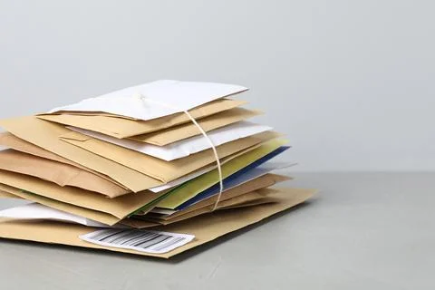 Post office. Stack of different paper envelopes on grey table, closeup. Spa.. Foto stock