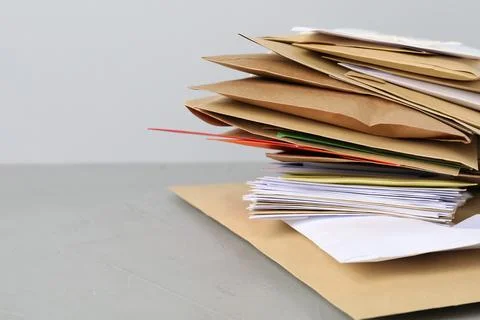 Post office. Stack of different paper envelopes on grey table, closeup. Spa.. Foto stock