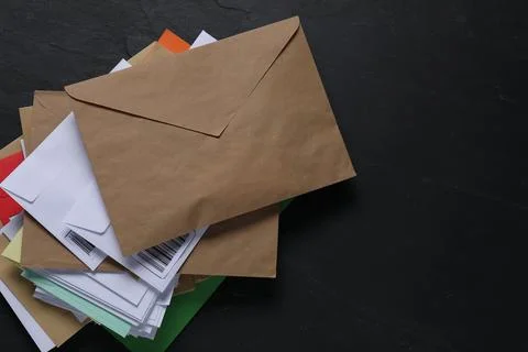 Post office. Stack of different paper envelopes on black table, top view. S.. Foto stock