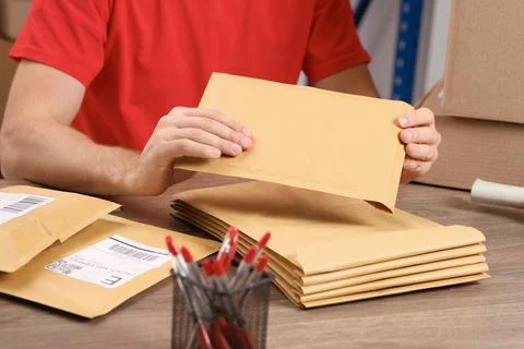 Post office worker with adhesive paper bags at counter indoors, closeup Stock Photos
