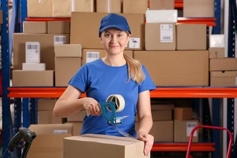 Post office worker packing parcel near rack indoors Photos