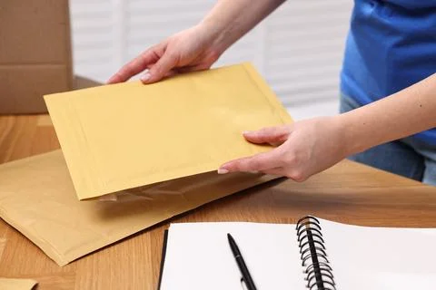 Post office worker packing parcel at wooden table indoors, closeup Foto stock