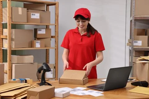 Post office worker packing parcel at wooden table indoors Photos
