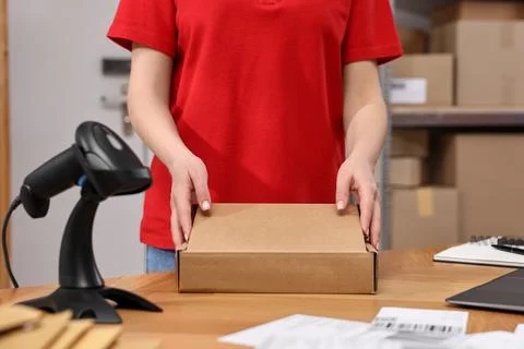Post office worker packing parcel at wooden table indoors, closeup Photos