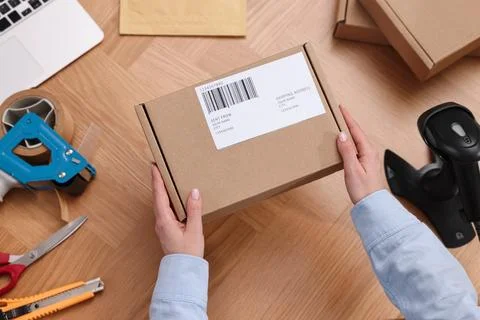 Post office worker packing parcel at wooden table, top view Photos