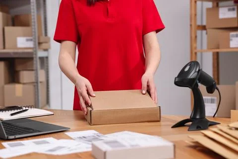 Post office worker packing parcel at wooden table indoors, closeup Photos