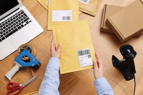 Post office worker packing parcel at wooden table, top view Photos