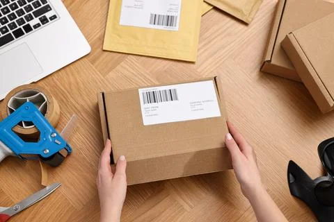 Post office worker packing parcel at wooden table, top view Photos