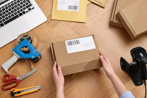 Post office worker packing parcel at wooden table, top view Photos