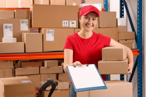 Post office worker with parcels and clipboard near rack indoors Photos