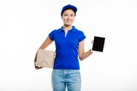 Post office worker poses at the camera holding a parcel and a tablet. Stock Photos