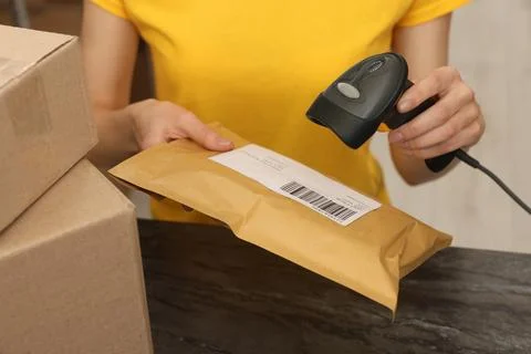 Post office worker with scanner reading parcel barcode at counter indoors, .. Photos