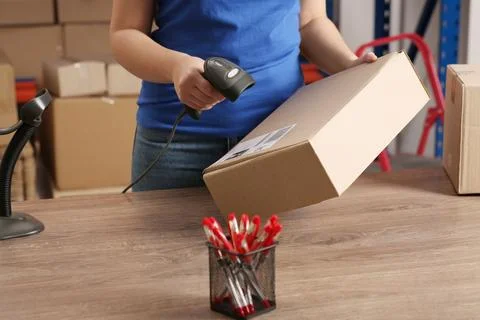 Post office worker with scanner reading parcel barcode at counter, closeup Stock Photos