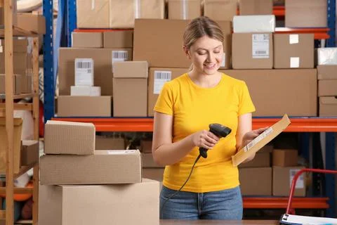 Post office worker with scanner reading parcel barcode indoors Photos