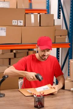 Post office worker with scanner reading parcel barcode at counter indoors Photos
