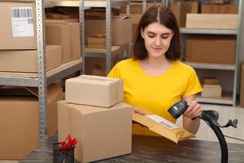 Post office worker with scanner reading parcel barcode at counter indoors Photos