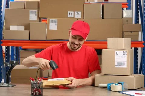 Post office worker with scanner reading parcel barcode at counter indoors Photos