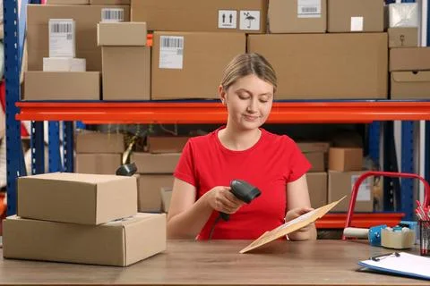 Post office worker with scanner reading parcel barcode at counter indoors Photos