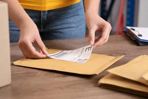 Post office worker sticking barcode on parcel at counter indoors, closeup Foto stock