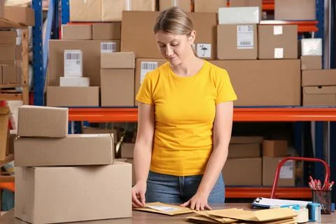 Post office worker sticking barcode on parcel at counter indoors Foto stock