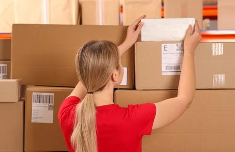 Post office worker taking parcel from rack indoors, back view Stock Photos