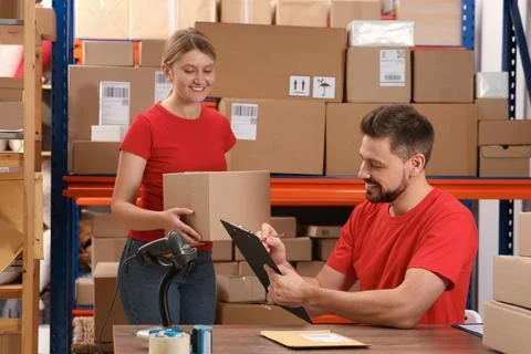 Post office workers checking parcel barcode indoors Foto stock