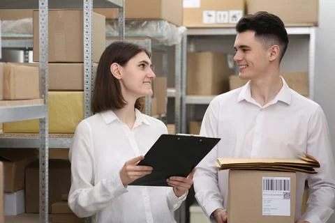Post office workers checking parcel barcode near rack indoors Stock Photos