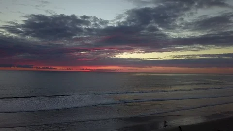 Post sunset drone view of beach with surfer walking with surfboard in San Diego Stock Footage 97155616